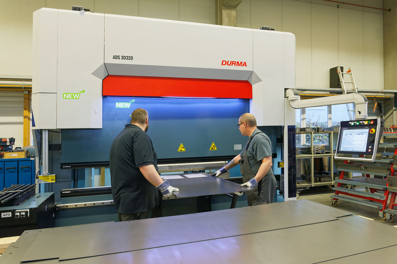 Zwei Mitarbeiter kanten ein großformatiges Blech an der Durma CNC-Abkantpresse